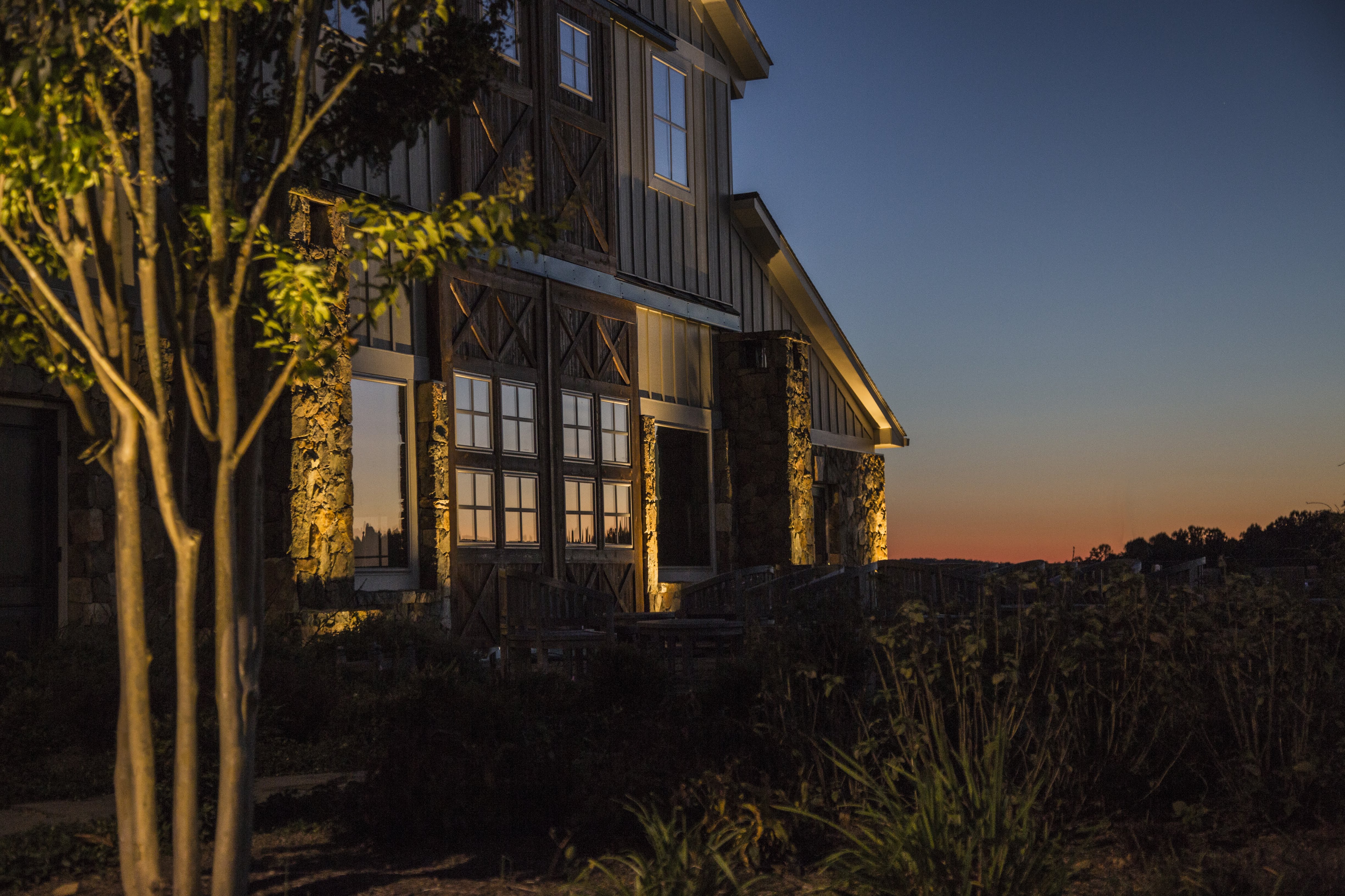 Professional outdoor lighting illuminating a Charlotte home and landscaping at sunset.